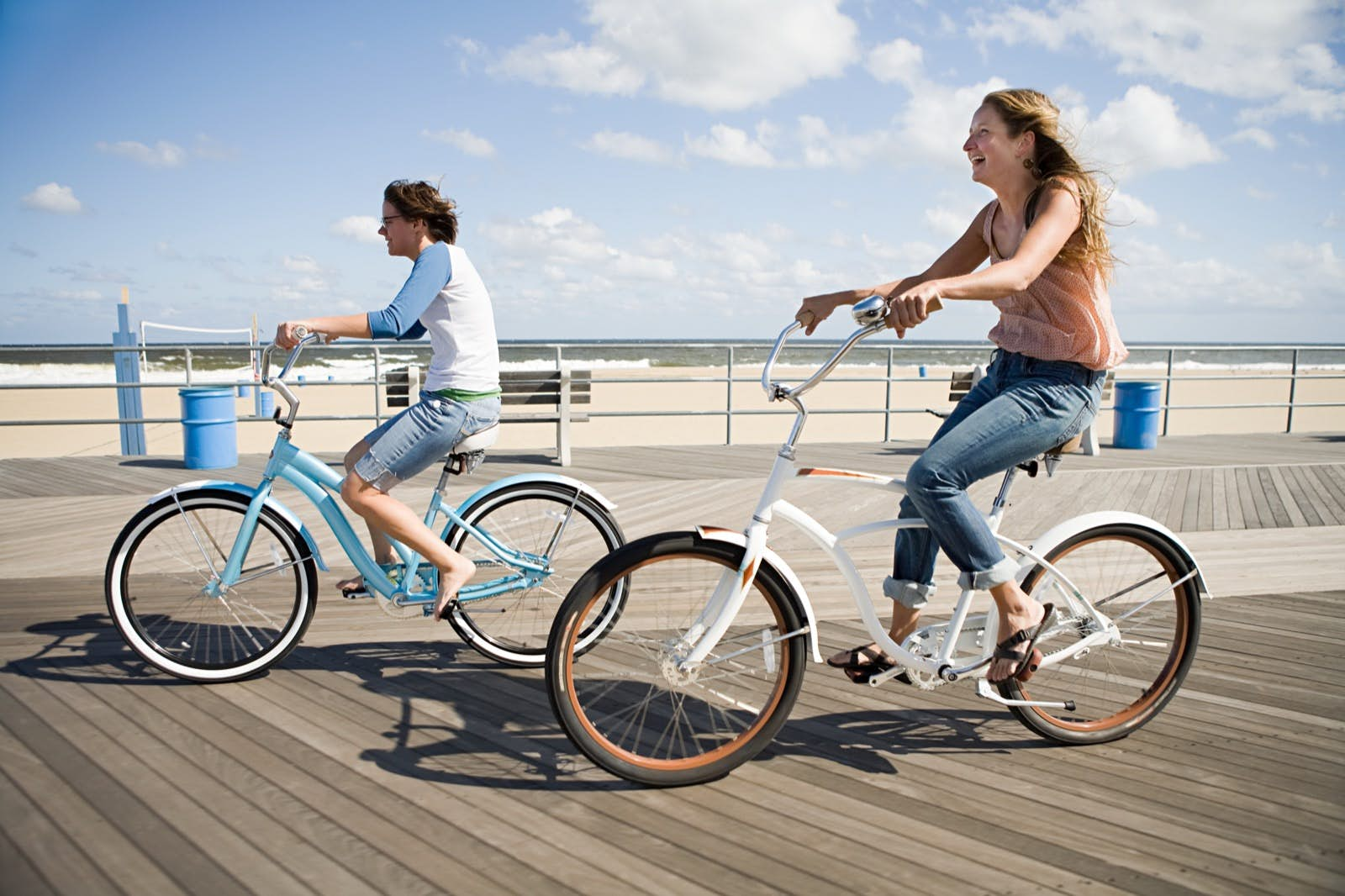 Two people ride bikes down a boardwalk